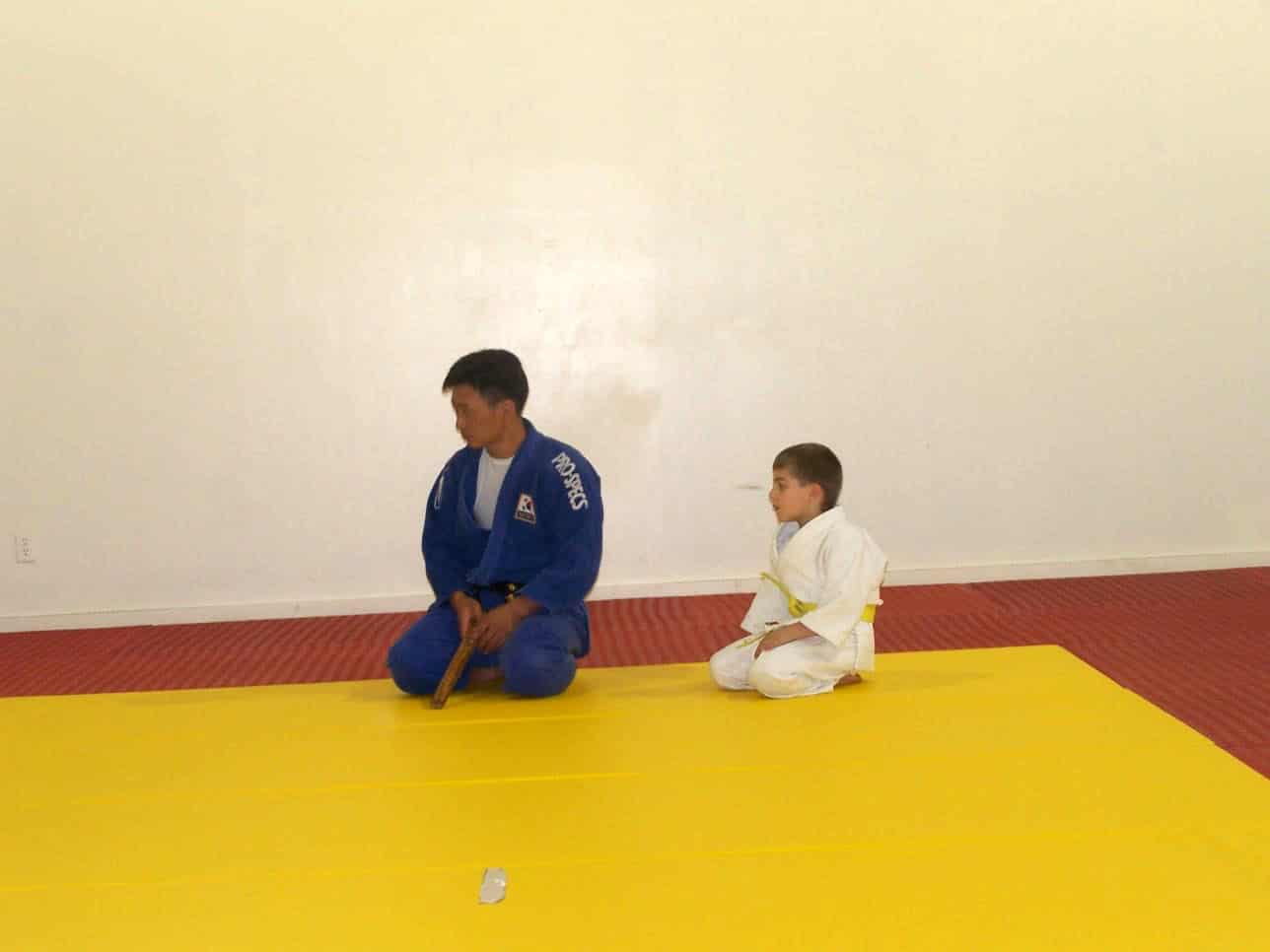 child sitting next to the judo head coach